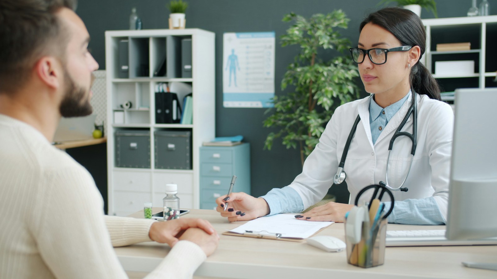 Una profesional de la salud conversa con una persona en su consultorio.